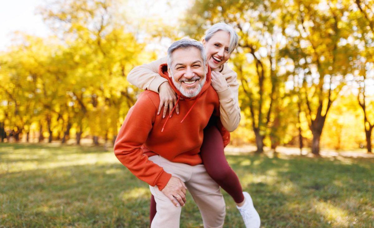 older couple in fall leaves smiling and having fun